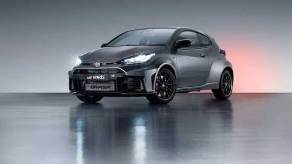 Toyota Yaris GR gris foncé garée dans un entrepôt avec les phares allumés
